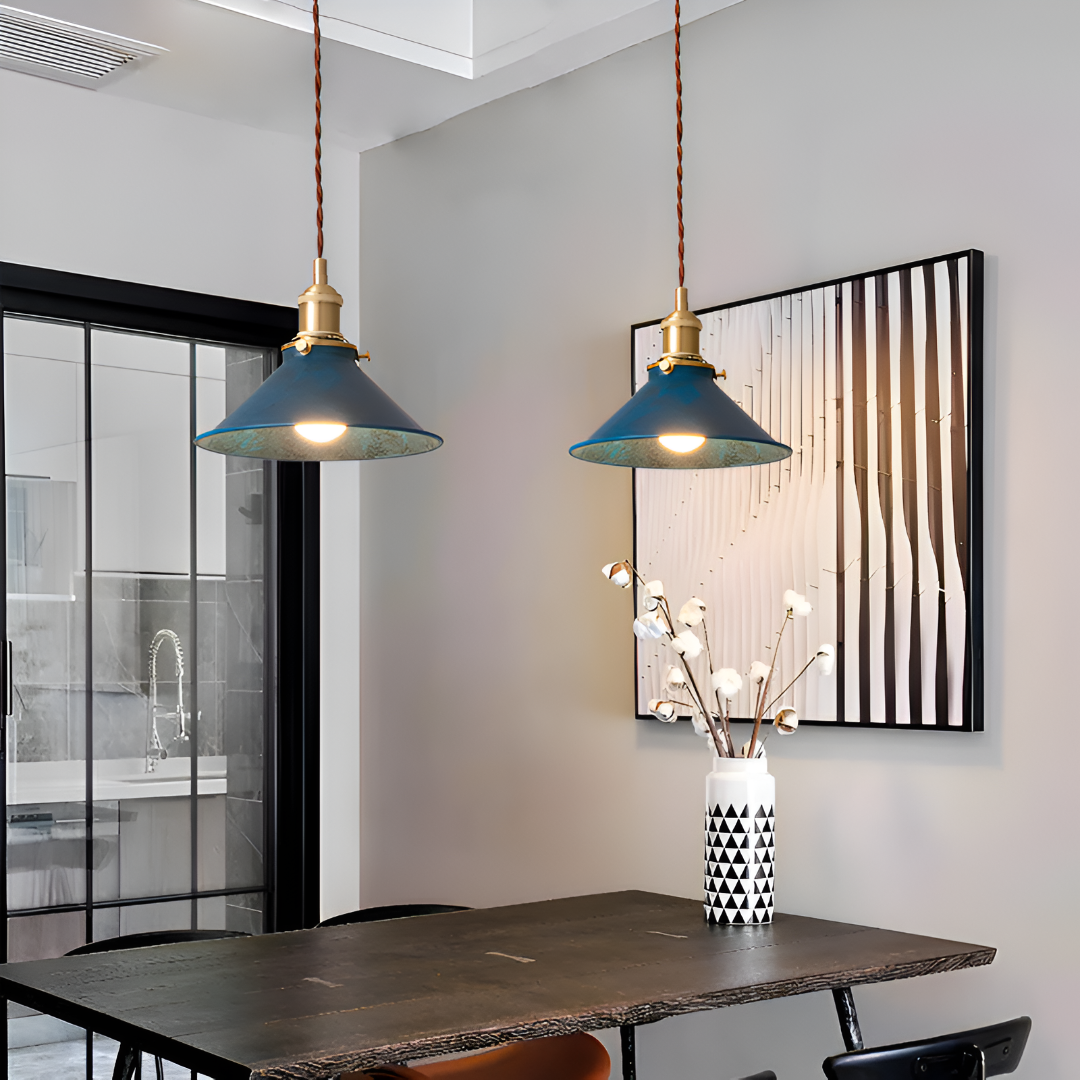 Modern interior with blue pendant lights, a vase with decorative branches, and a framed abstract painting.