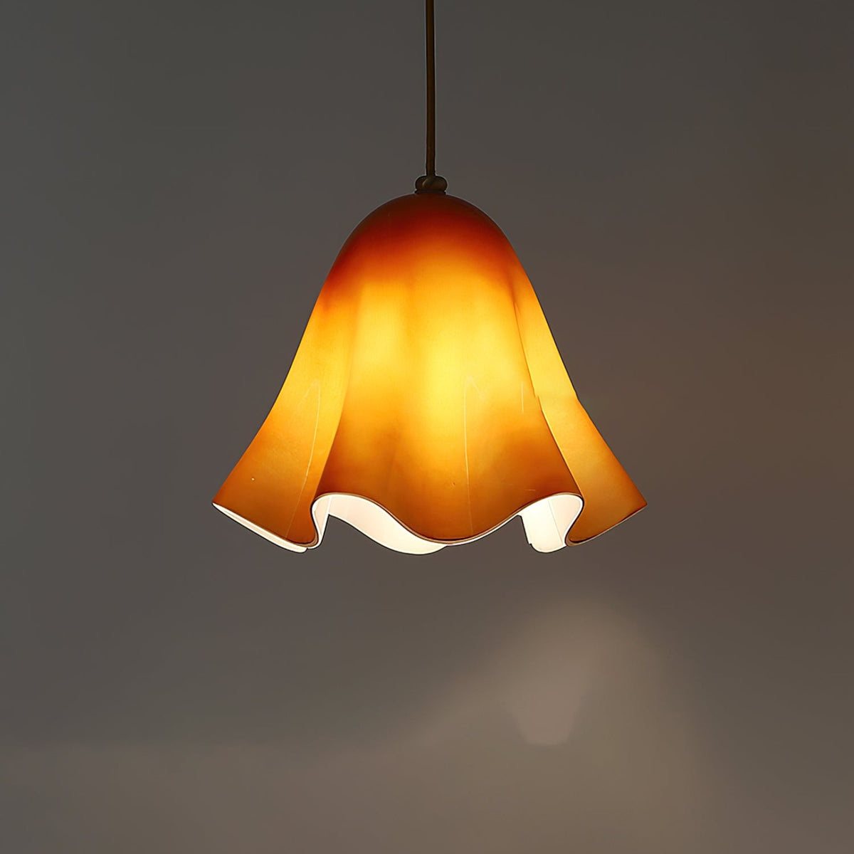 Amber glass skirt pendant light glowing