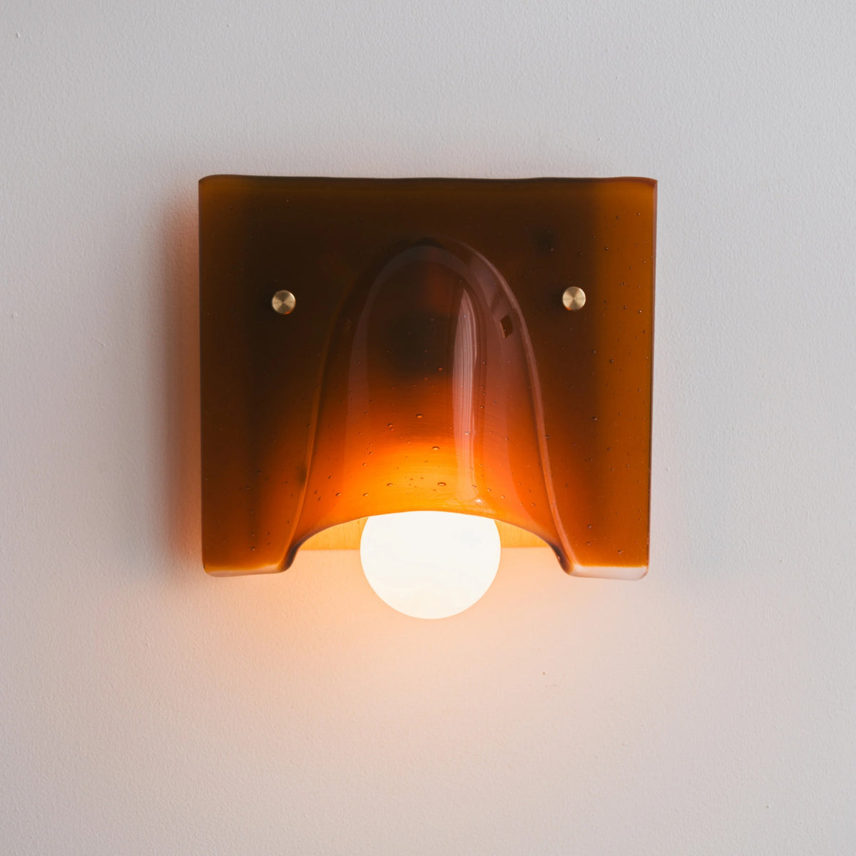 Linnea amber single head wall light glowing warm on the wall