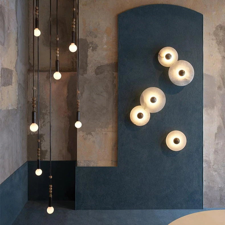 Alabaster disc wall lights arranged on a blue architectural feature wall