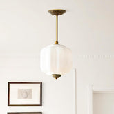 Kabocha ribbed milk glass pendant with antique brass canopy on a white wall