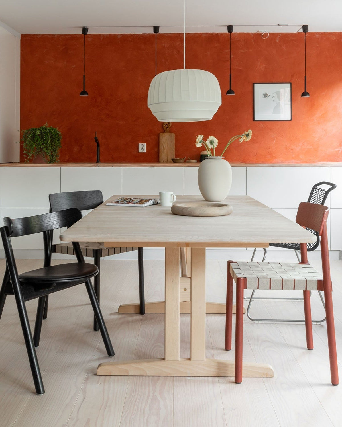 Wren pendant over a round dining table against a terracotta wall