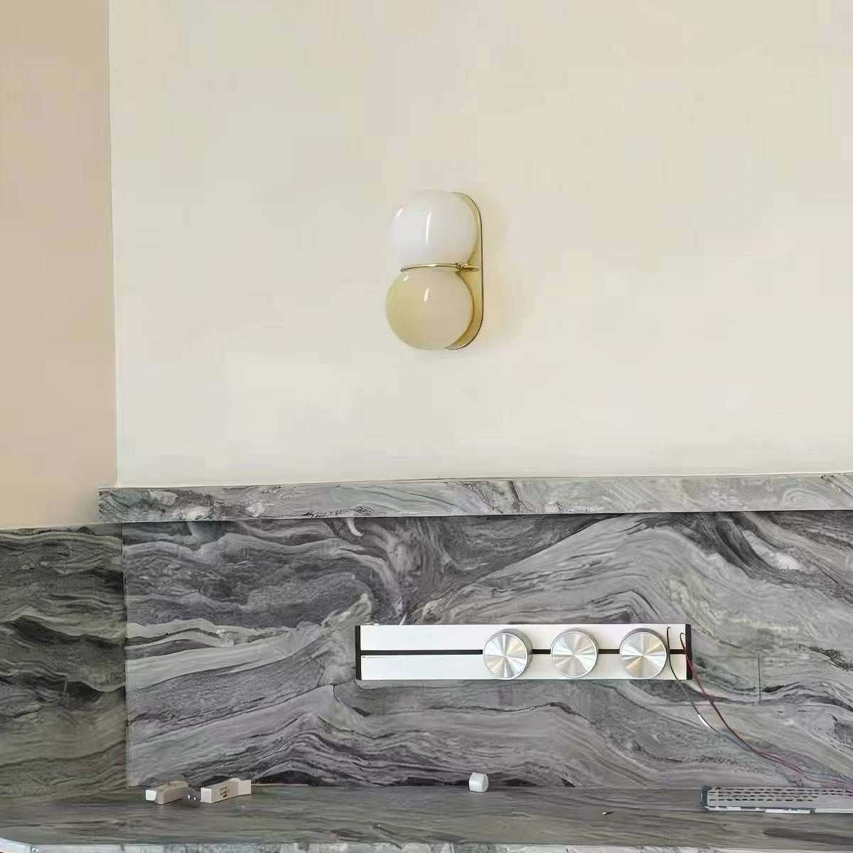 Maren cream twin glass wall light on a wall above a marble splashback