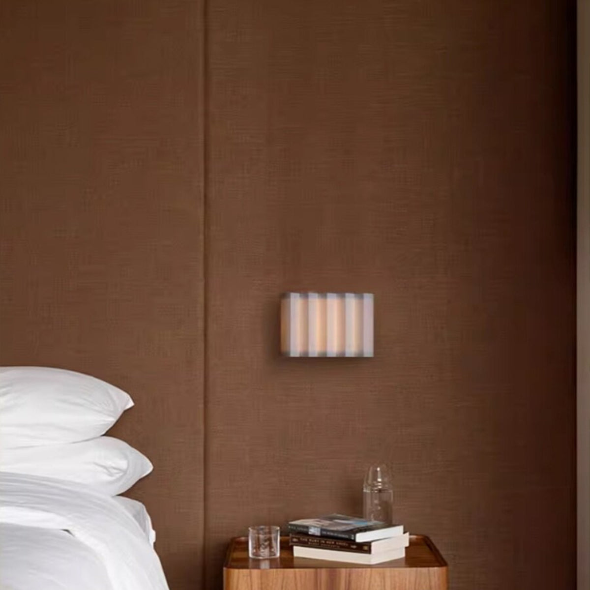 Wave pleated fabric wall lamp above a bedside table
